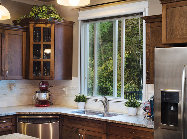 Traditional kitchen with sliding window above sink, featuring wood cabinets and garden view