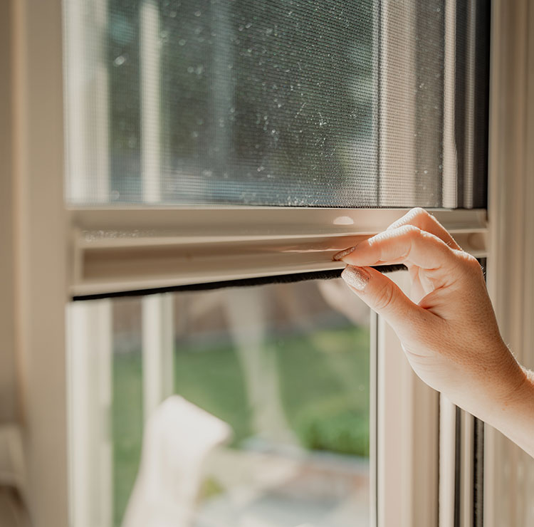 Close-up of hand pulling down retractable window screen, showing smooth operation and clean installation