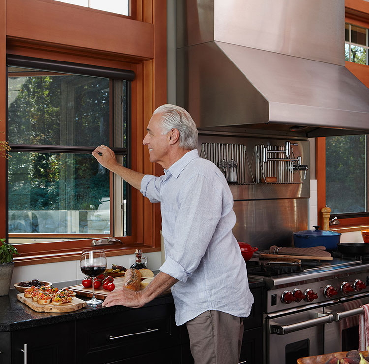 Modern kitchen with wood-framed windows, professional range, and food preparation on black countertops