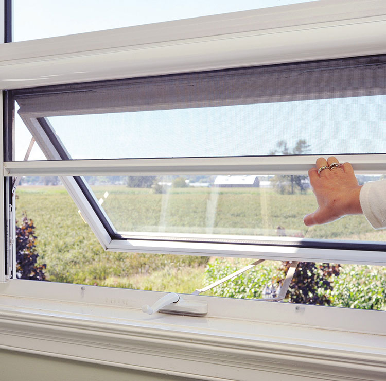 Hand operating awning window with retractable screen, overlooking scenic countryside