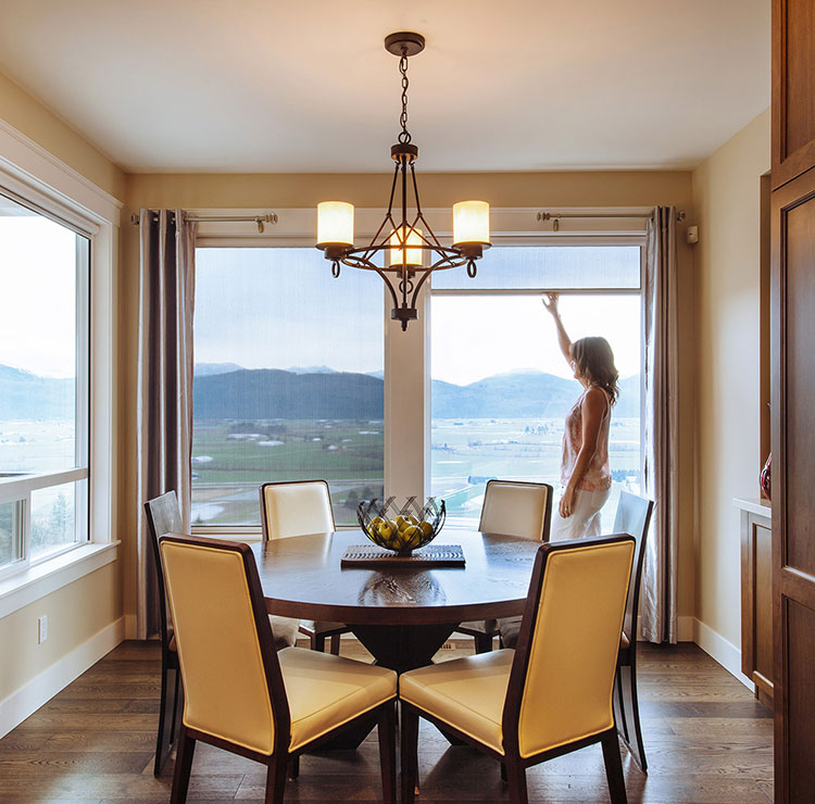 Elegant dining room with mountain view through large windows, featuring cream leather chairs