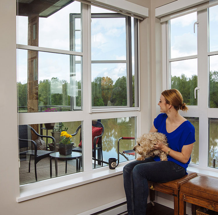 Bright sunroom with retractable screens, featuring lakeside view and casual seating area